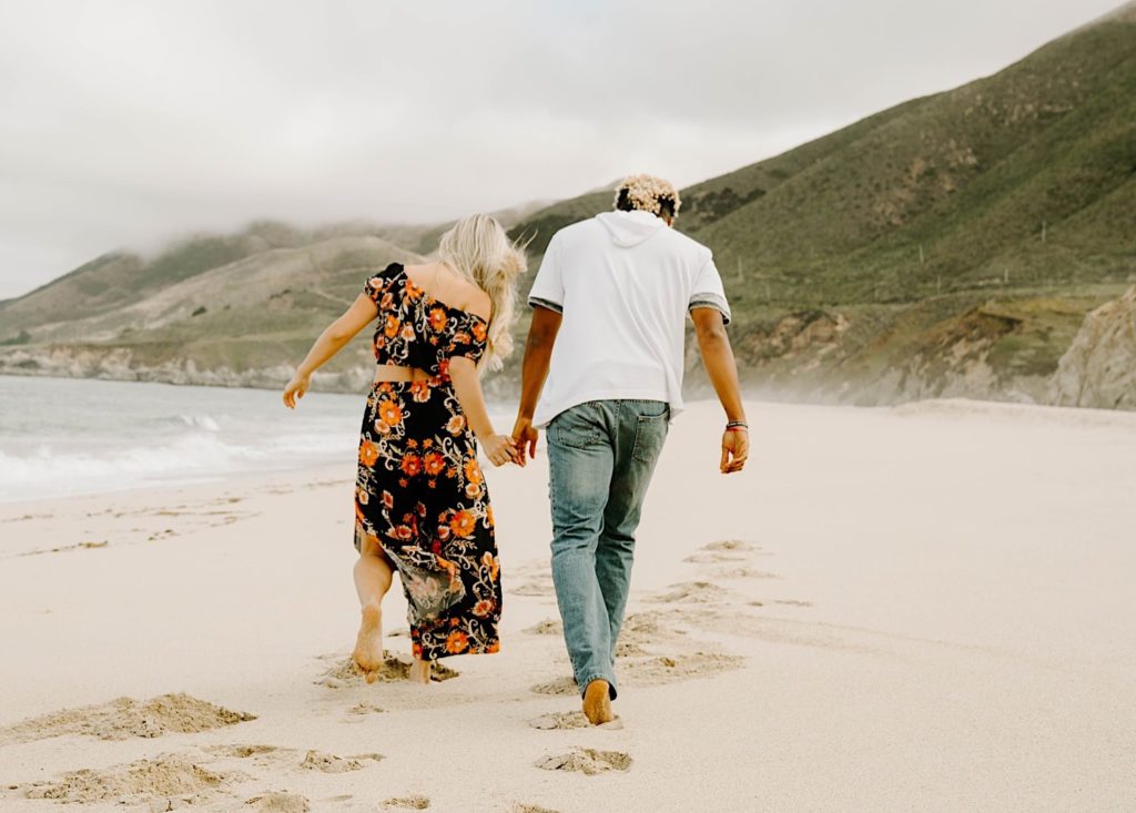 couple walking away holding hands at garapata state beach california