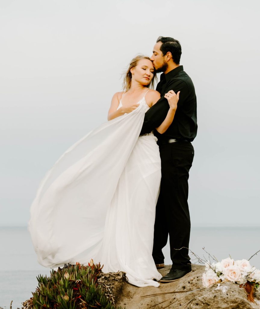 guy kissing girl on forehead cliff side elopement big sur