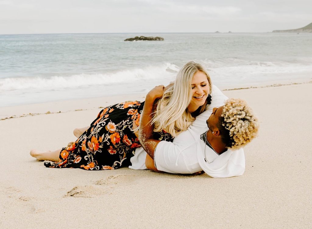 couple rolling in the sand at Garapata State beach California.