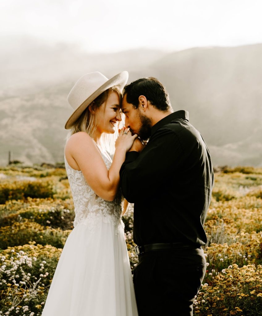 guy kissing girl's hands cliff side elopement big sur