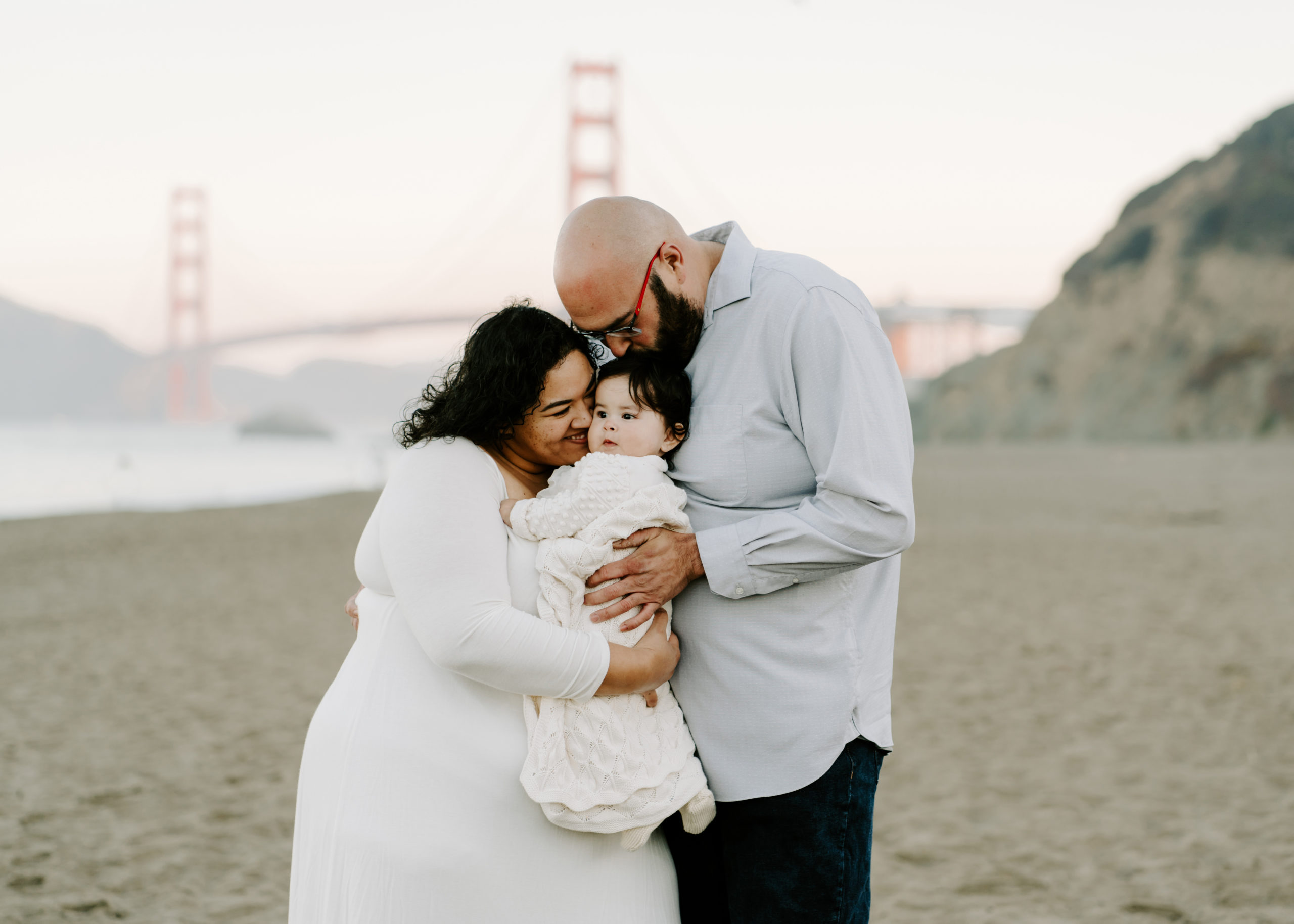 Family hugging on Baker Beach in San Francisco by family photographer Torez Marguerite.