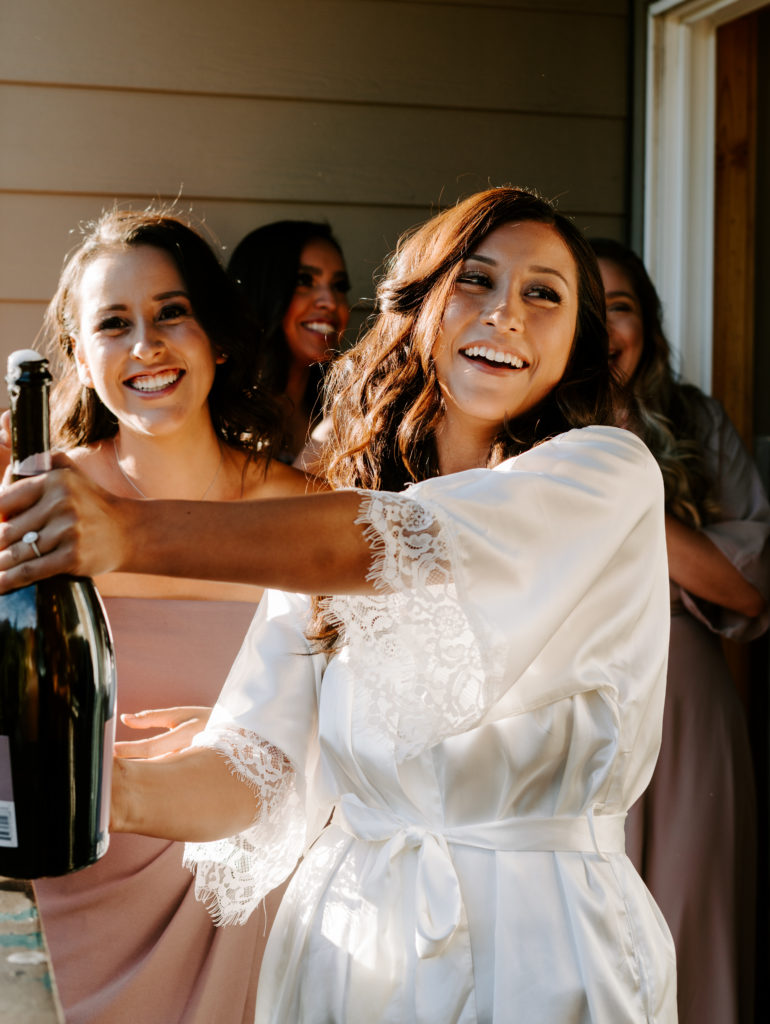 Bride popping champagne bottle.