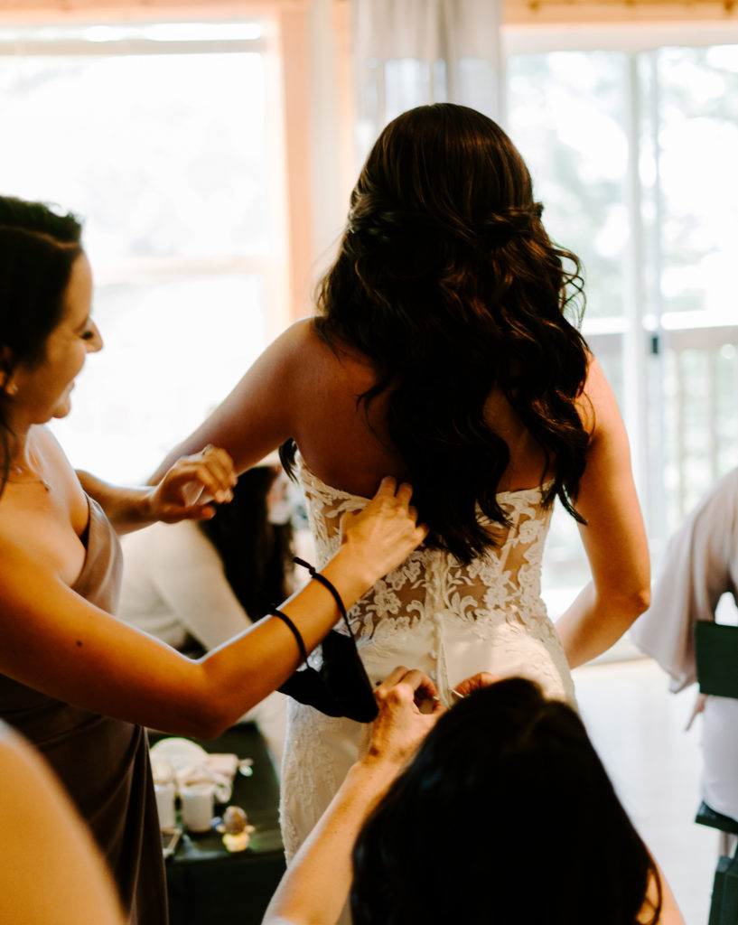 Bride getting help with putting on wedding dress