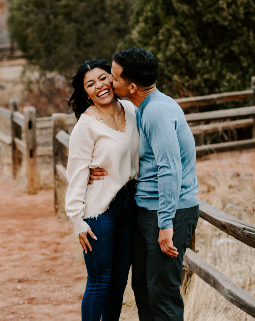 Guy kissing girlfriend's cheek while she laughs.