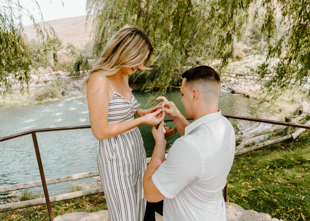 Couple putting on ring after wedding proposal.