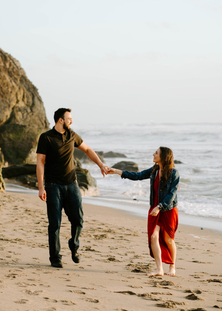 Man and woman holding hands on the beach.
