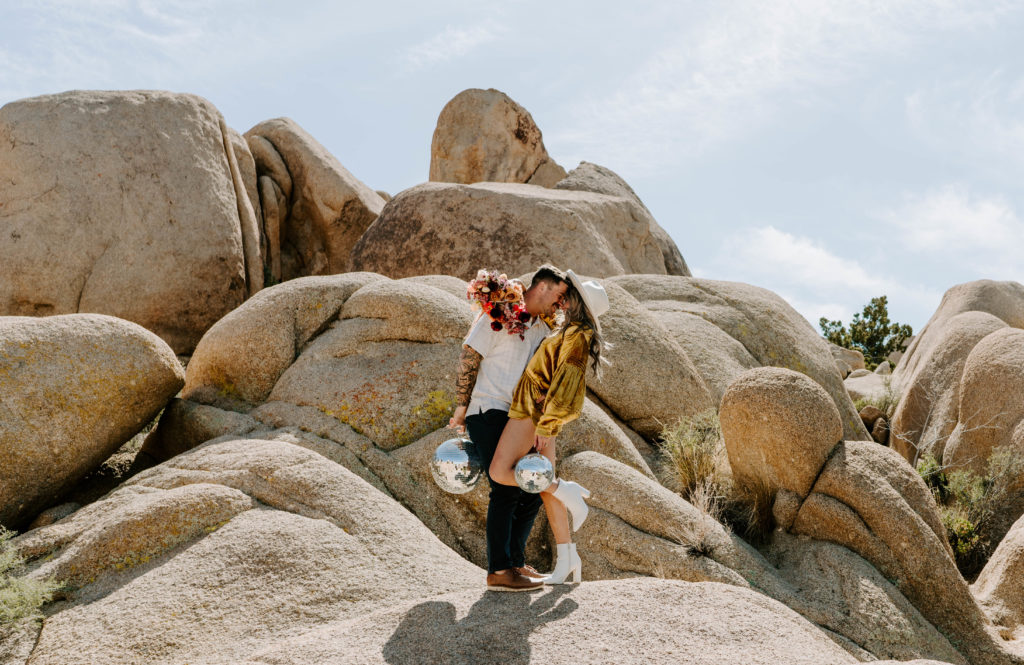 Couple face to face while holding disco balls in Joshua Tree.