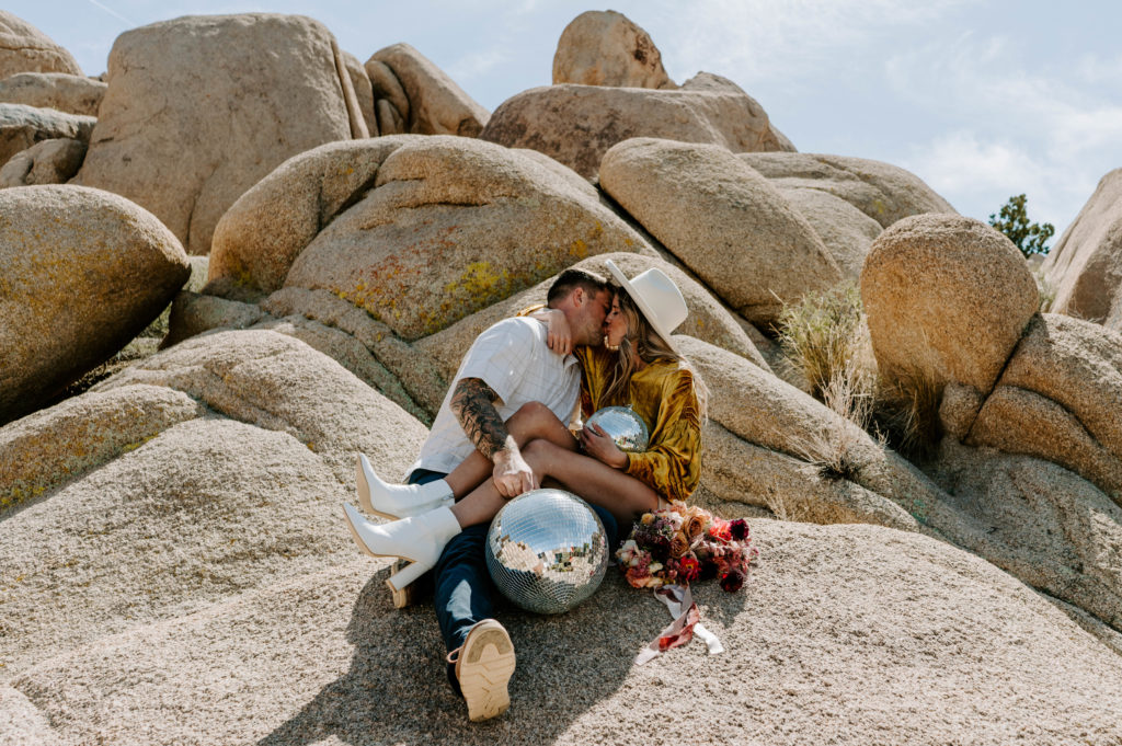 Man and woman kissing while sitting on Jumbo Rocks.