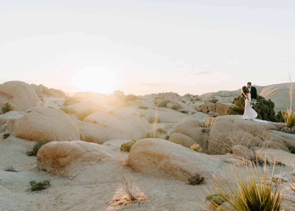 Groom and bride standing on rock in Joshua Tree.