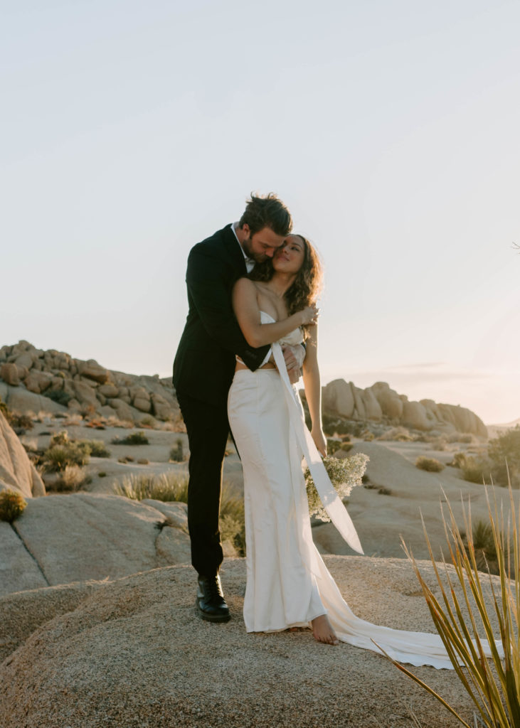Groom cuddling bride.
