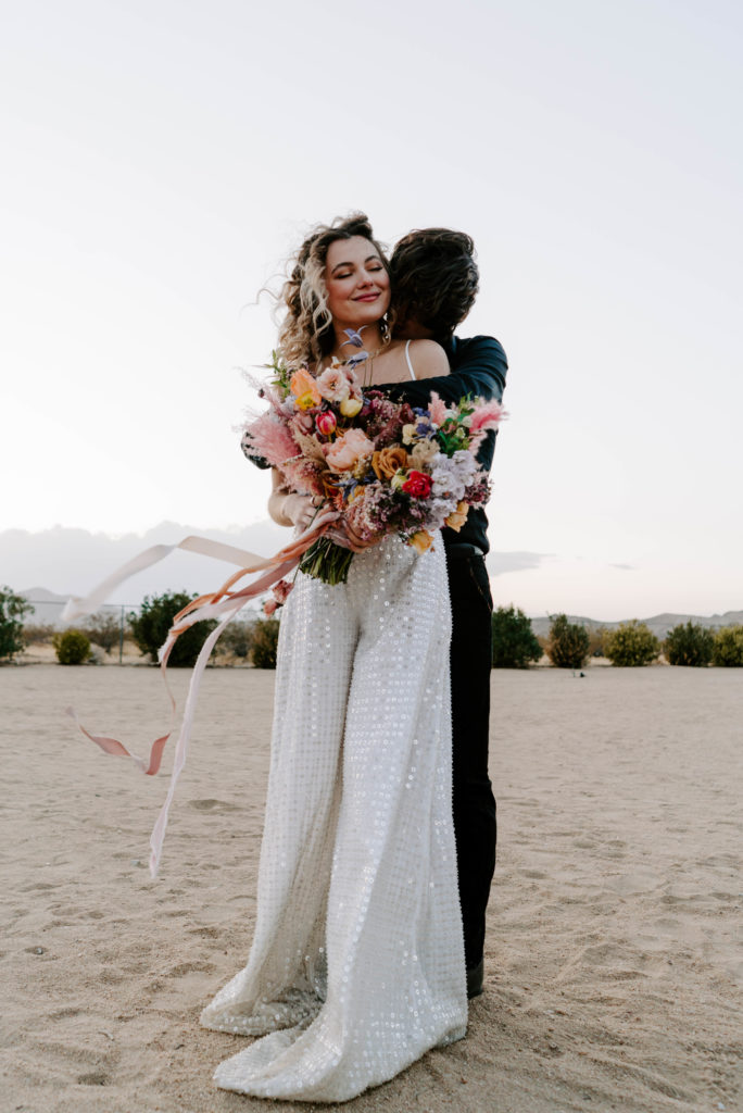 Groom hugging bride from behind.