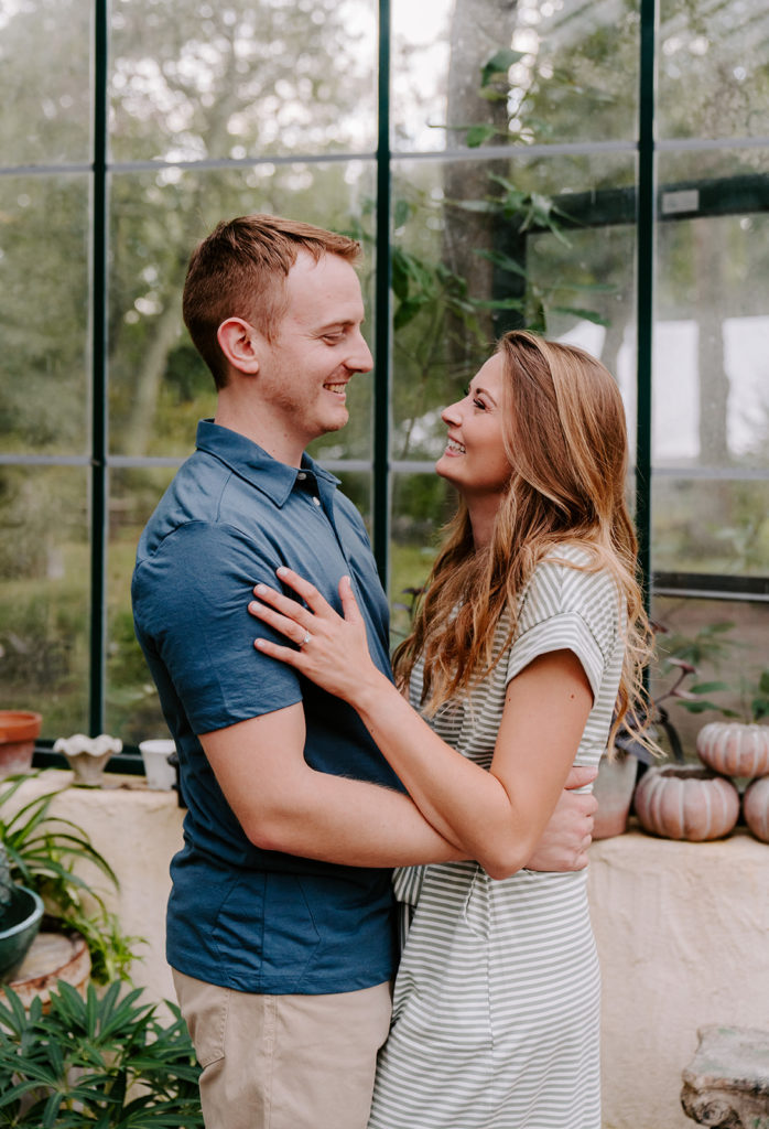 Couple smiling at each other during their greenhouse photoshoot.