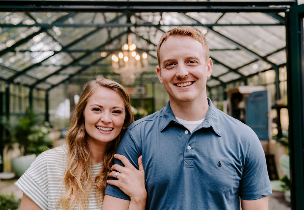 Couple smiling during greenhouse photoshoot.