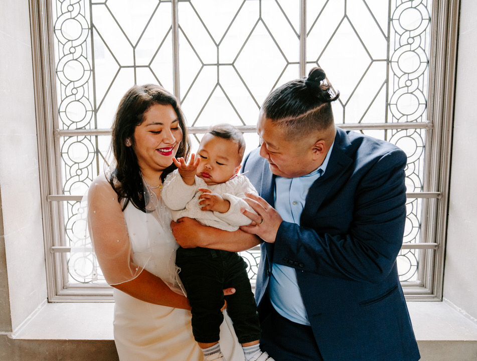 bride and groom with their baby posing for San Francisco City Hall wedding Photographer