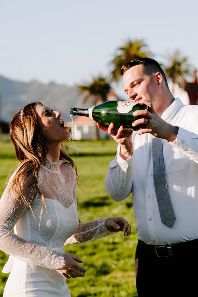 Groom pouring champagne in bride's mouth.