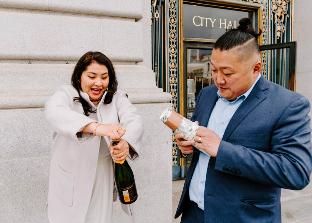 Bride popping champagne outside of San Francisco City Hall.