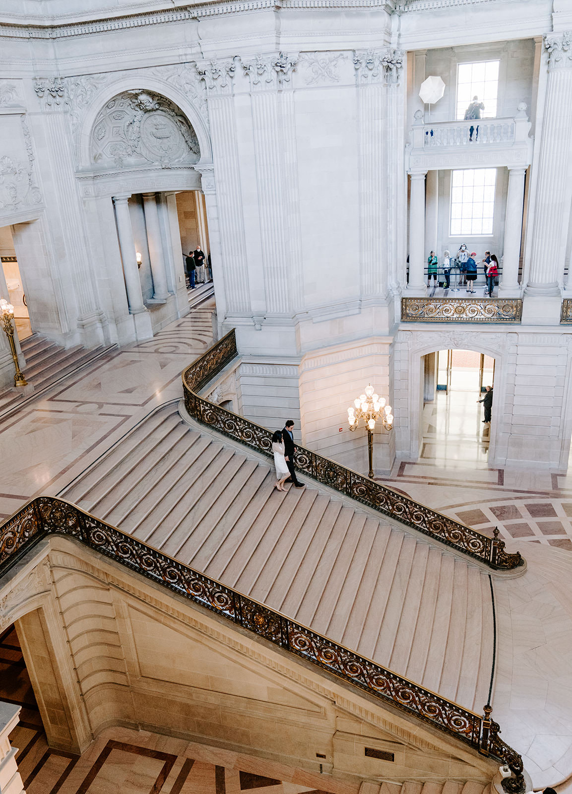 Couple walking down grand Staircase SF City Hall.