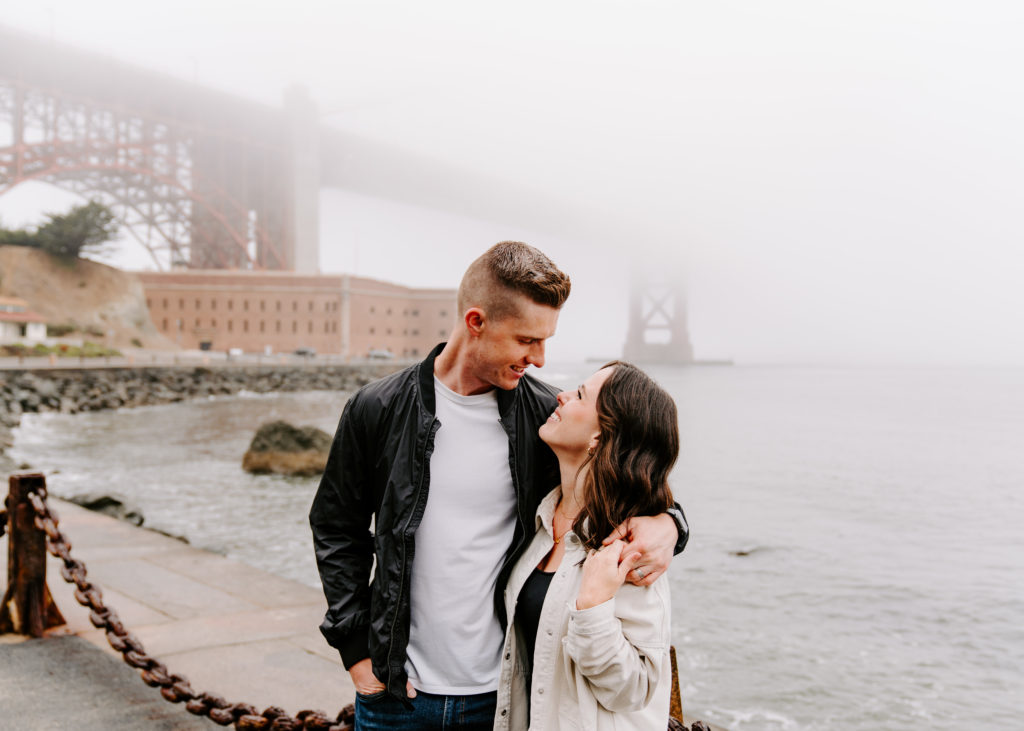 Couple looking at each other at Golden Gate Bridge.