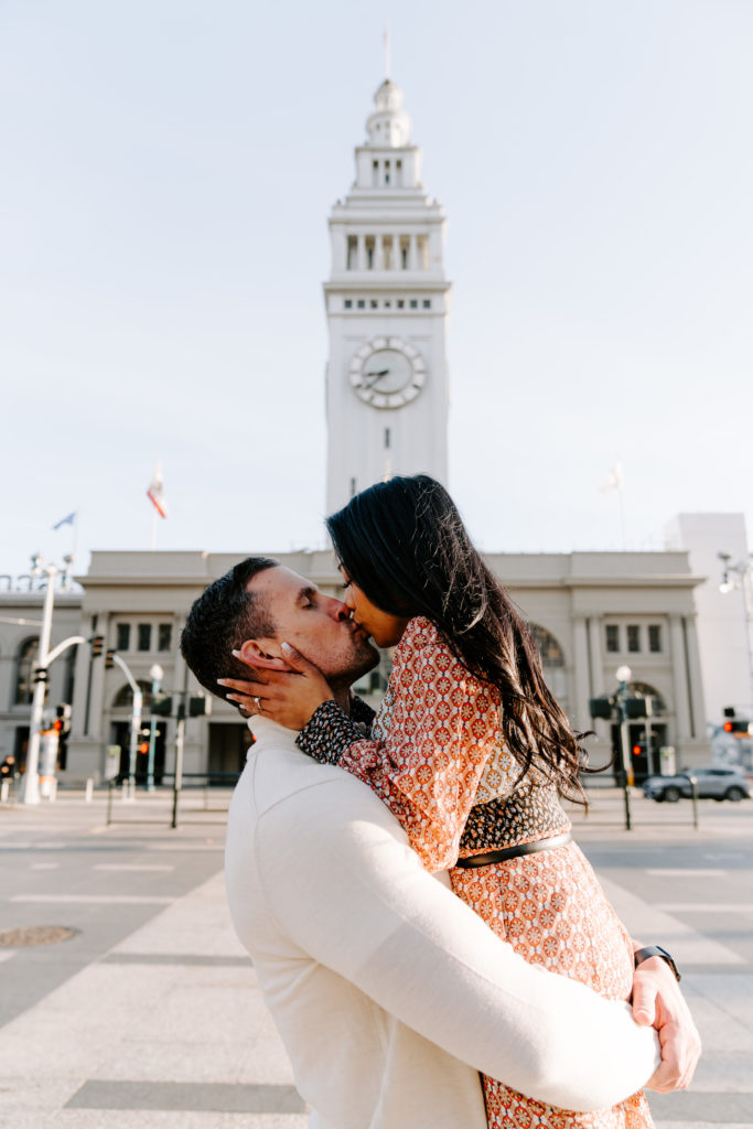 Couple kissing in front of the ferry building.
