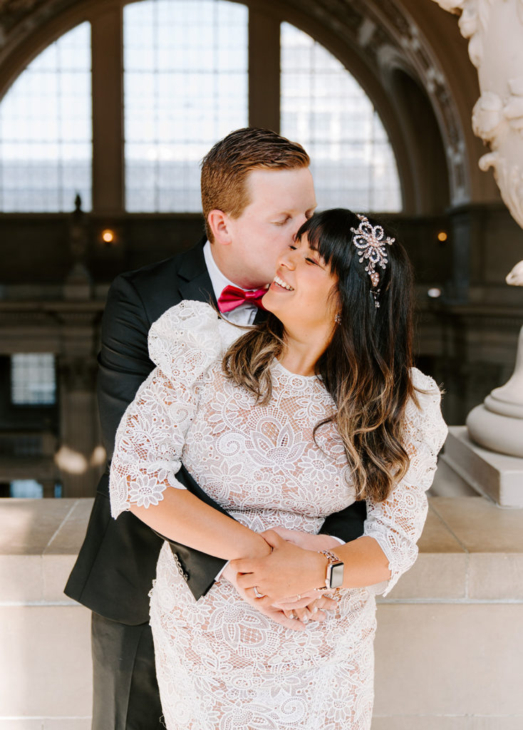 bride and groom snuggling in sf city hall
