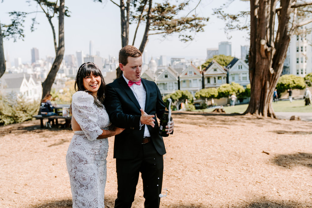 couple popping champagne at alamo square sf