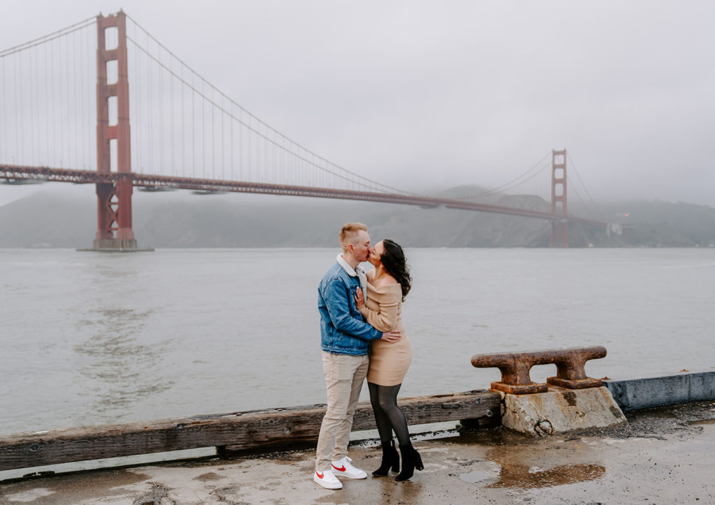 couple kissing in front of the golden gate bridge
