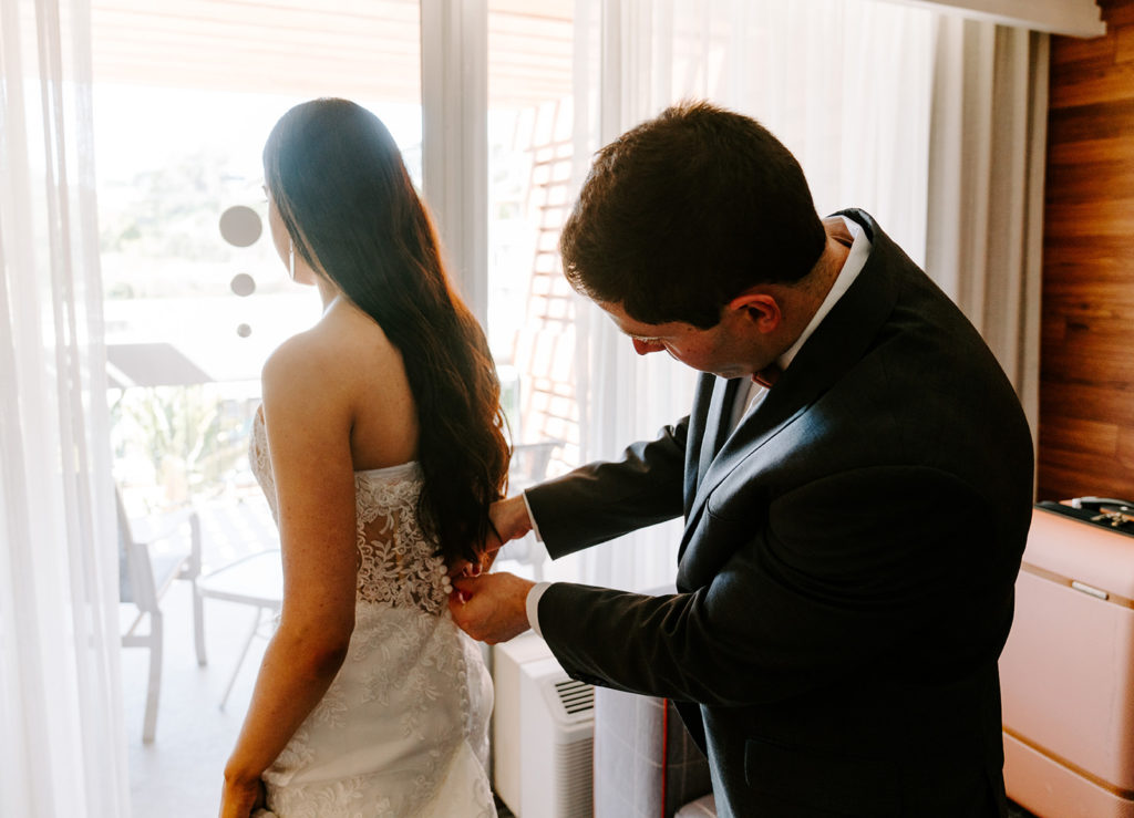 groom helping bride with dress
